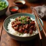 Close-up of a delicious Korean Ground Beef and Rice Recipe, topped with sesame seeds and green onions, served in a white bowl.